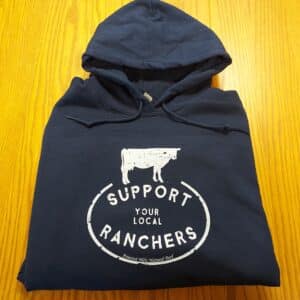 Support Your Local Ranchers hoodie on a wood surface