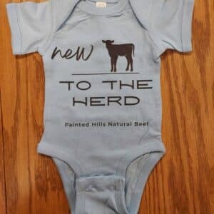 new to the herd onesie in light blue on a wooden surface Western baby onesies